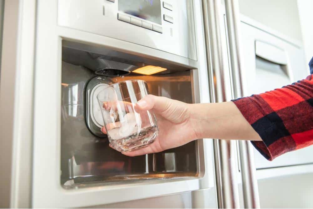 Photo of someone getting a glass of water at a refrigerator water dispenser