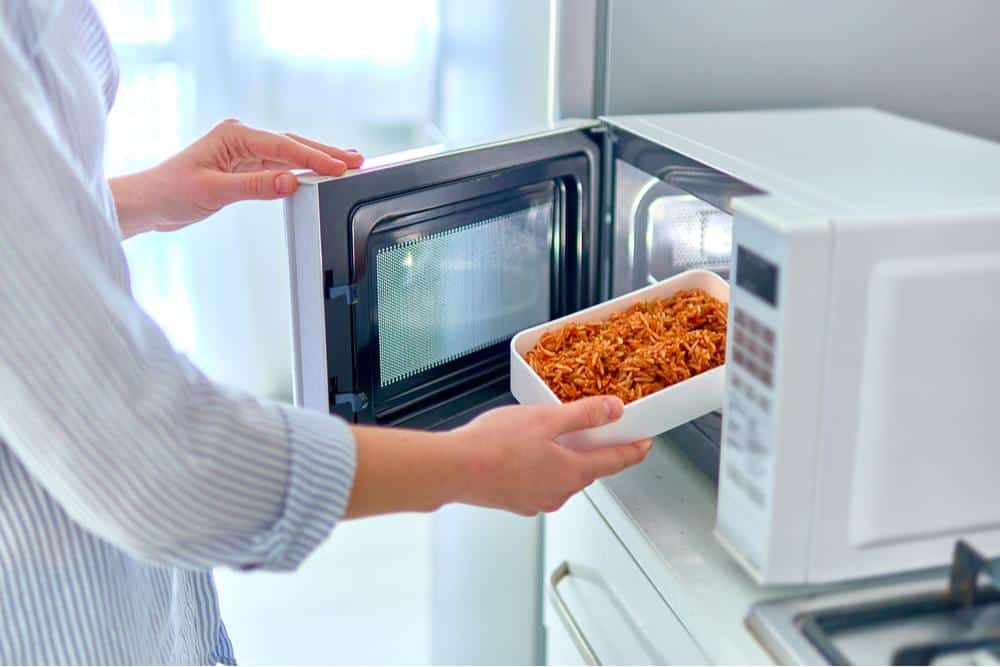 Photo of a man removing pasta from a microwave