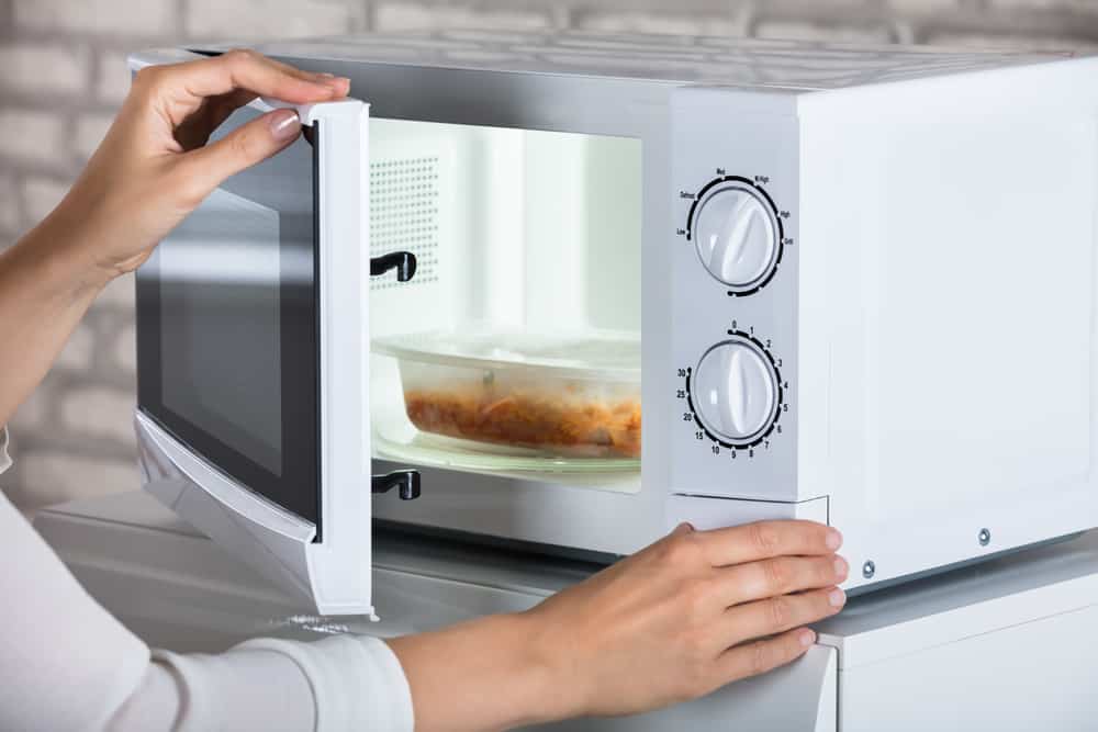 Photo of a woman heating up lunch in a microwave