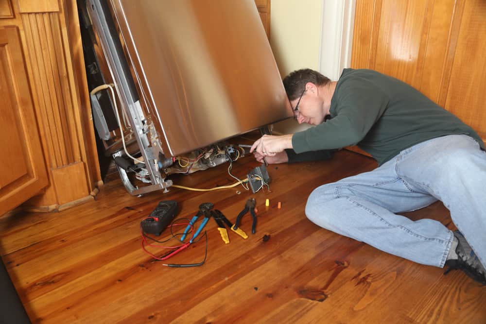 Photo of an appliance repairman fixing a dishwasher