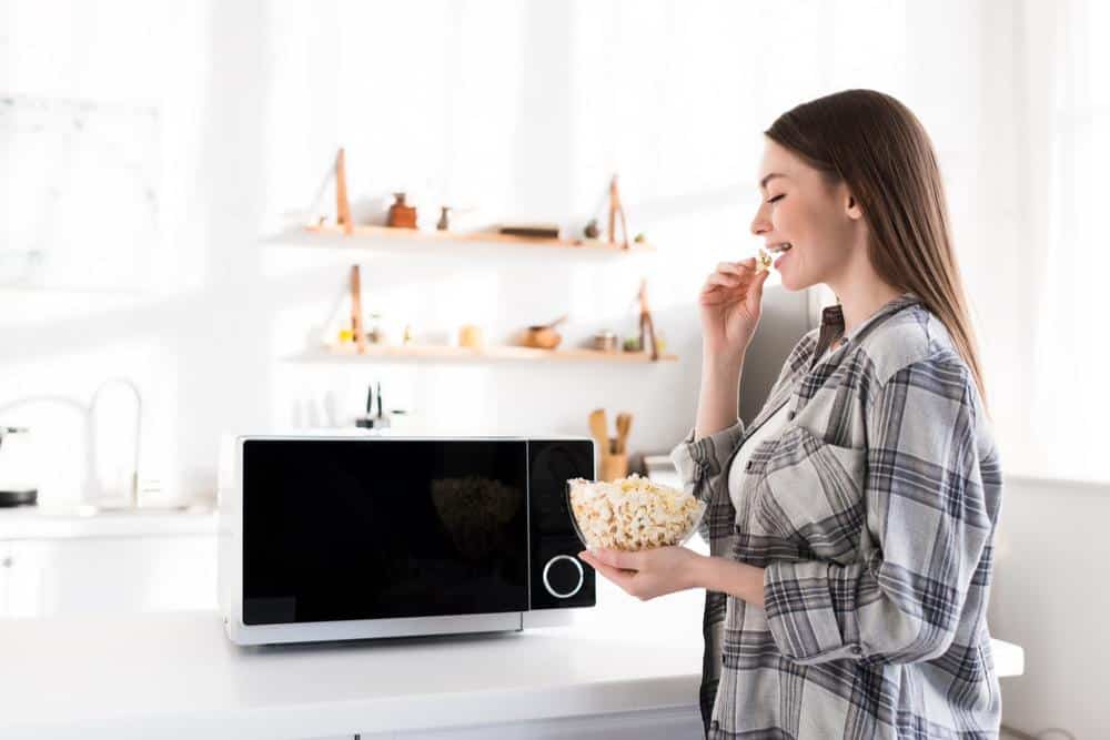 Photo of woman eating microwaved popcorn