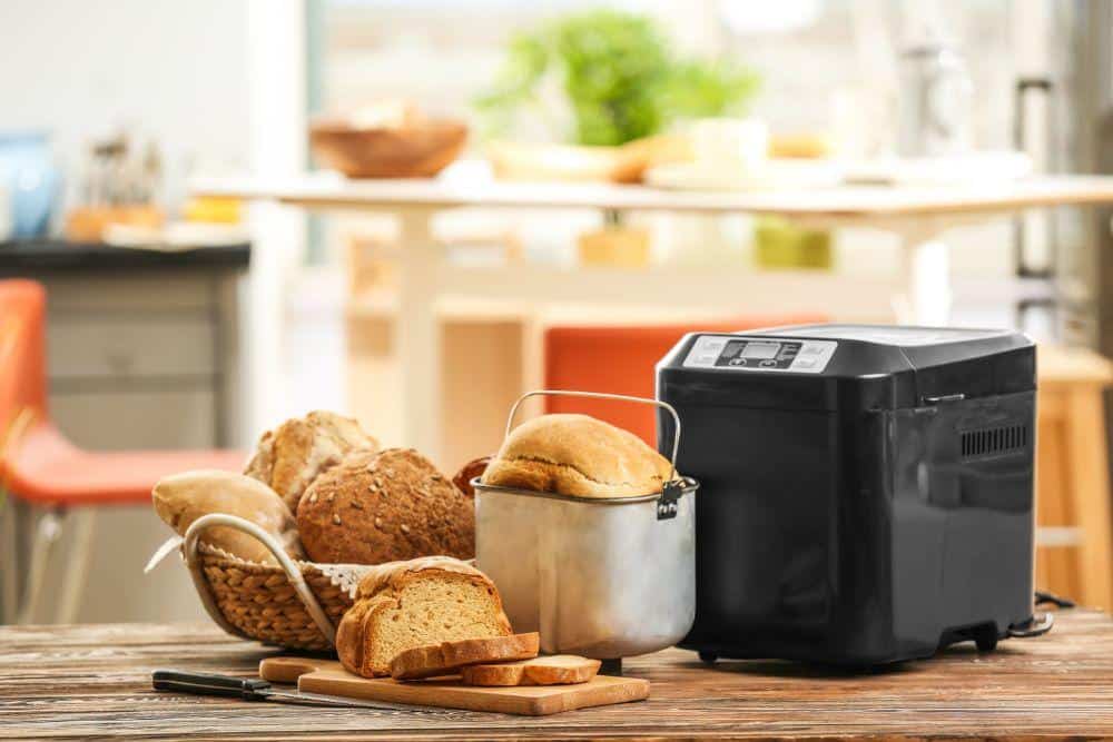 Photo of a Bread Machine Next to Homemade Bread Loaves