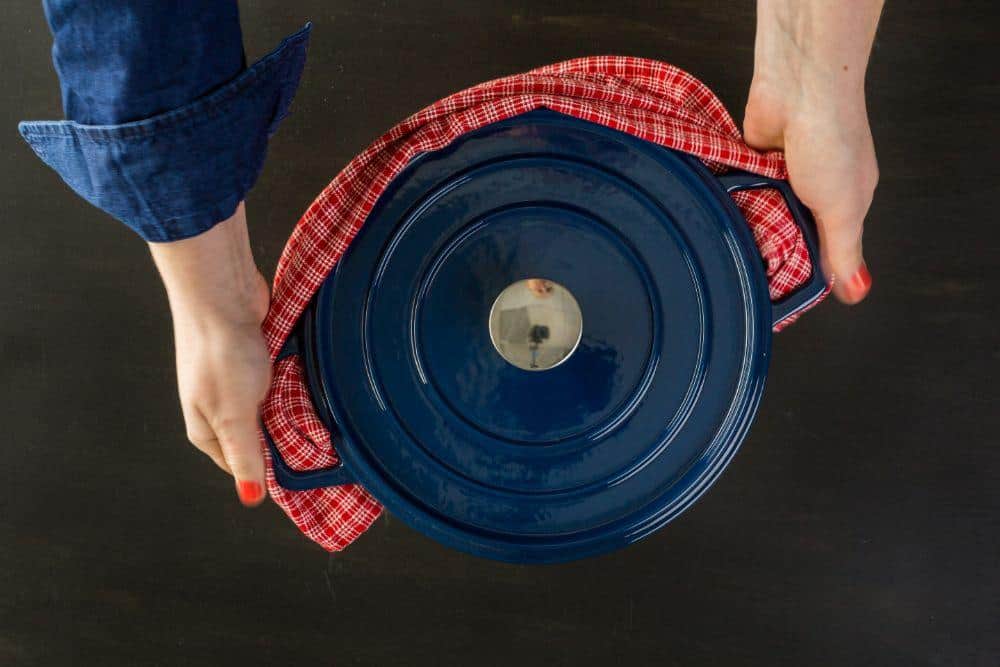 Photo of a Hot Dutch Oven Being Held With a Dish Towel