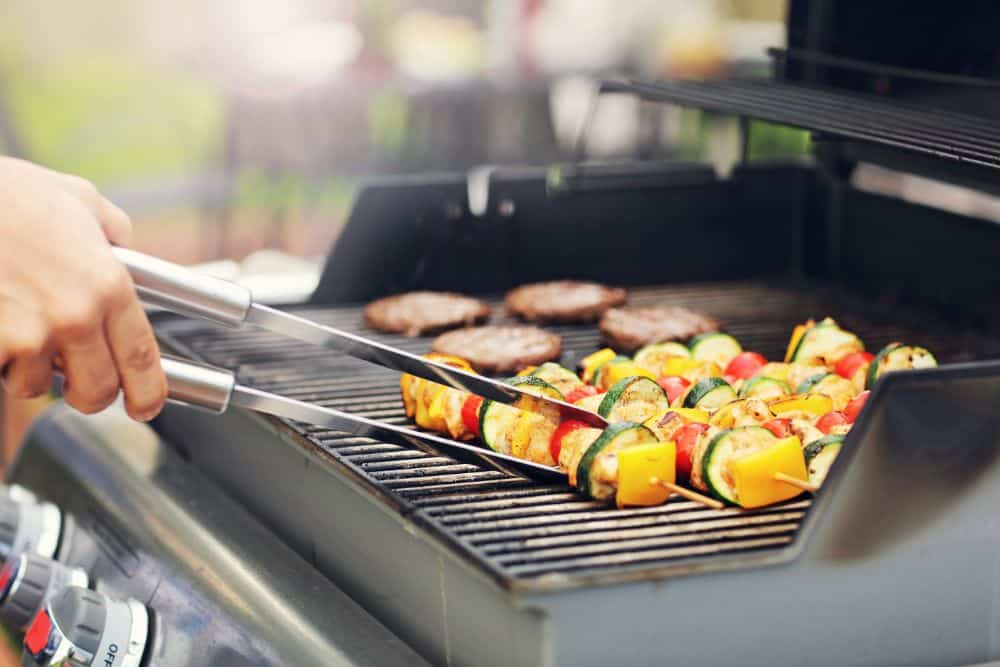 Photo of Someone Cooking Burgers and Vegetables on a Gas Grill