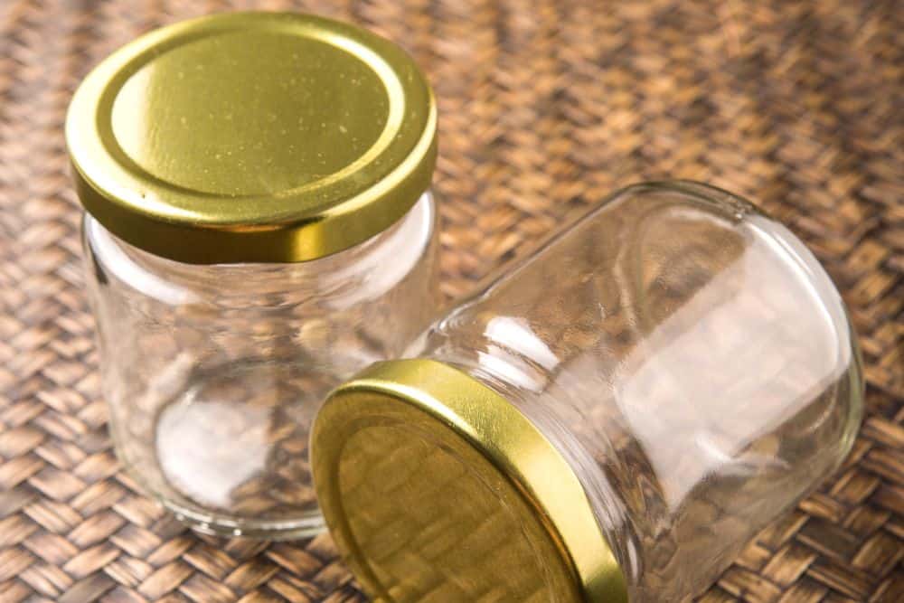 Two glass jars with gold lids on a rattan background.