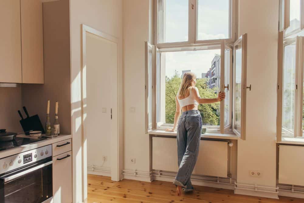 A woman opening a window to allow proper ventillation
