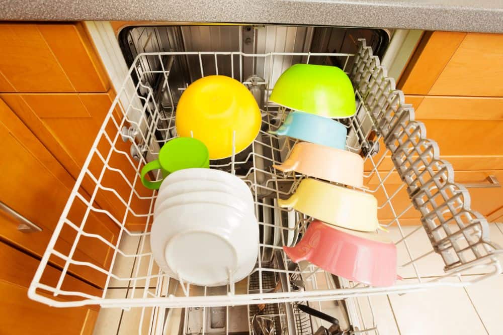 A dishwasher full of colorful dishes in a kitchen, demonstrating the safety of plastic in dishwashers.