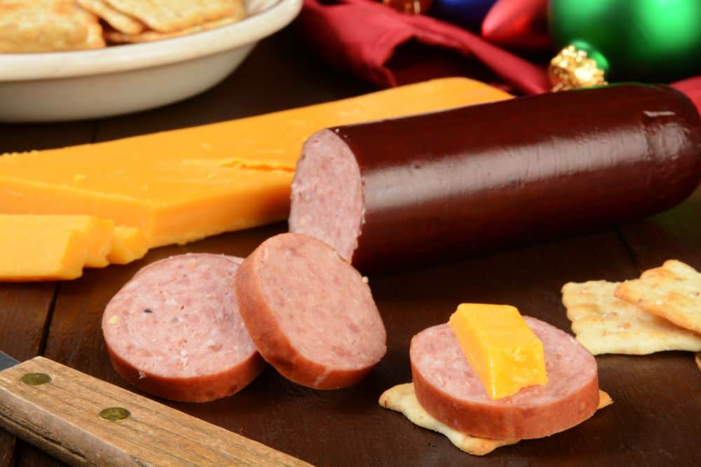 Sausage, cheese and crackers displayed on a wooden table.