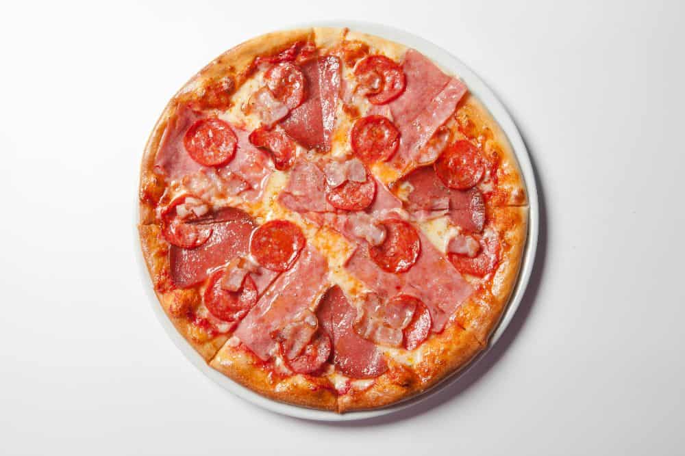 A pizza with ham and tomatoes.
