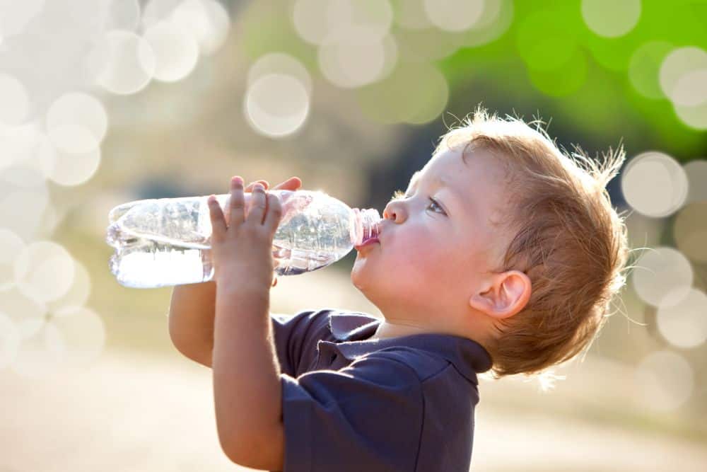 A child drinking from a plastic bottle.